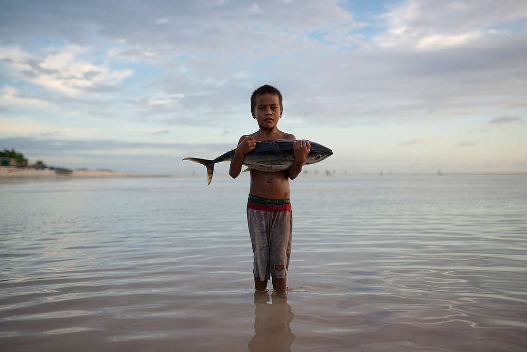 Boy with Tuna Fish Stands in Sea. © Christian Åslund / Greenpeace