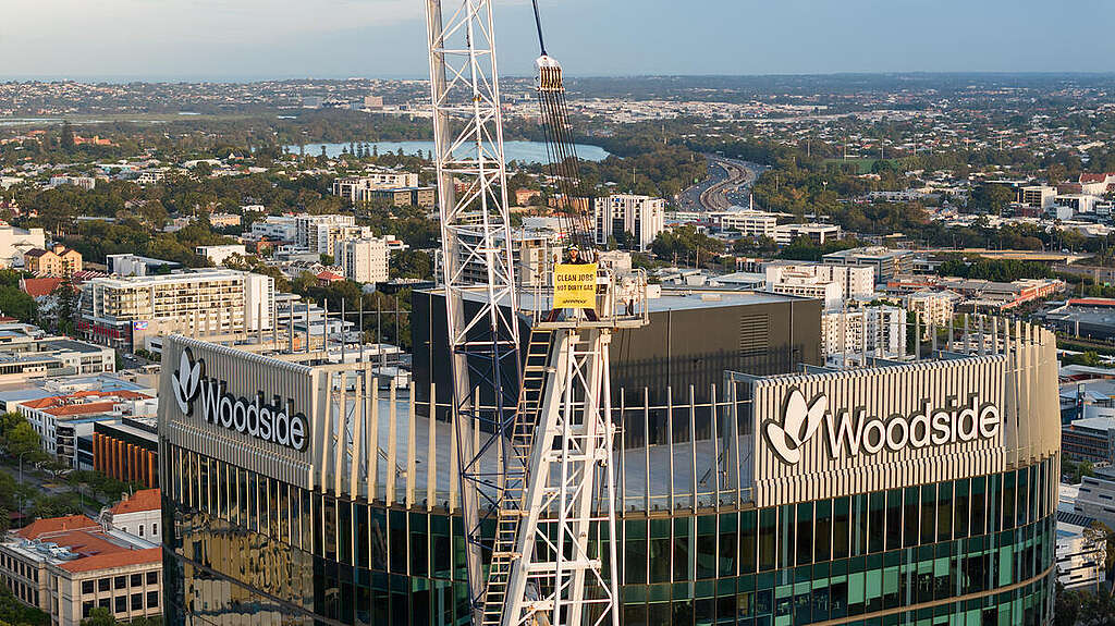 Greenpeace Australia activist holds 'Clean Jobs, Not Dirty Gas' banner from a crane outside Woodside's headquarters in Perth.